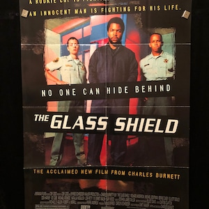 May include: Movie poster for the film "The Glass Shield" starring Ice Cube. The poster features a dark background with the title in large white letters. The tagline reads "A rookie cop is fighting a police conspiracy. An innocent man is fighting for his life."