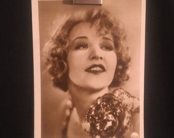 Może przedstawiać: Czarno-biała, vintage'owa pocztówka z portretem aktorki Betty Compson. Ma na sobie jasną sukienkę z dużym kwiatem na ramieniu. Na pocztówce widnieje napis "Betty Compson" wydrukowany na dole.