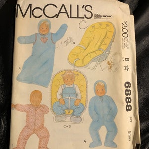 May include: McCall's sewing pattern number 6888 for a baby's outfit. The pattern includes instructions for a hooded sleeper, a jumpsuit, and a baby seat. The pattern is for sizes 6 months.