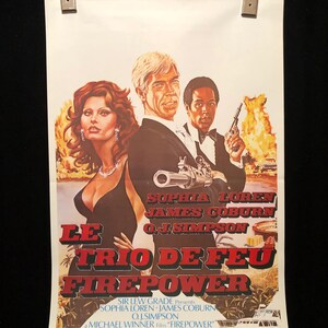 以下が含まれることがあります： ソフィア・ローレン、ジェームズ・コバーン、O.J.シンプソン主演の映画「ル・トリオ・デ・フェ: ファイアーパワー」の映画ポスター。ポスターには、3人の俳優がドラマチックなポーズをとっているカラフルなイラストが描かれており、背景には熱帯の島とヨットが描かれている。