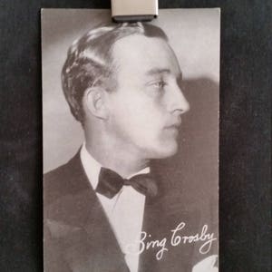 Peut inclure: Photographie en noir et blanc de Bing Crosby portant un costume et un nœud papillon. La photo est signée "Bing Crosby" à l'encre noire. La photo est imprimée sur une carte blanche avec le texte "Made in U.S.A." en bas.