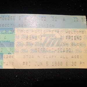 Puede incluir: Un boleto azul claro y verde para un concierto benéfico para un amigo. El boleto es para un asiento de admisión general, sección G2, fila 16, asiento 1200. El concierto es en el Metro en Chicago el 5 de junio de 1998 a las 6:30 PM.