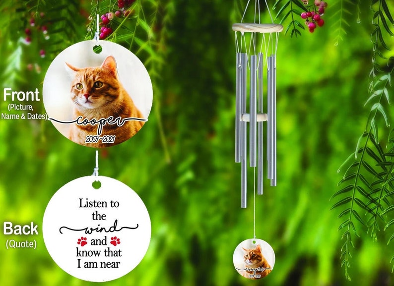 May include: A memorial wind chime with a photo of a ginger cat named Cooper, with the years 2009-2021. The back of the ornament has the quote "Listen to the wind and know that I am near" with paw prints.