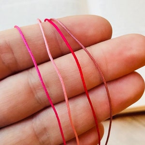 Puede incluir: Cuatro carretes de hilo de bordar en tonos de rosa, rojo y coral.