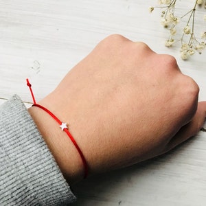 May include: A red string bracelet with a small silver star charm.
