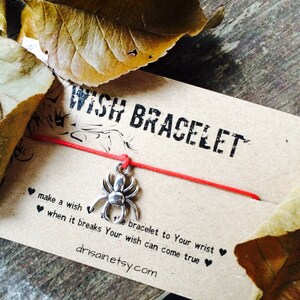 May include: Red string bracelet with a silver spider charm. The card reads "WISH BRACELET make a wishte bracelet to Your wrist ❤❤ when it breaks Your wish can come true❤ drisain.etsy.com"