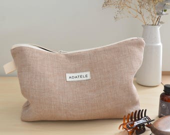 May include: A light brown linen zippered pouch with a white zipper and a white label that says "ADATELÉ".