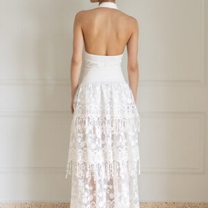 May include: A white halter top with a white lace skirt. The skirt has multiple layers and a fringe trim.