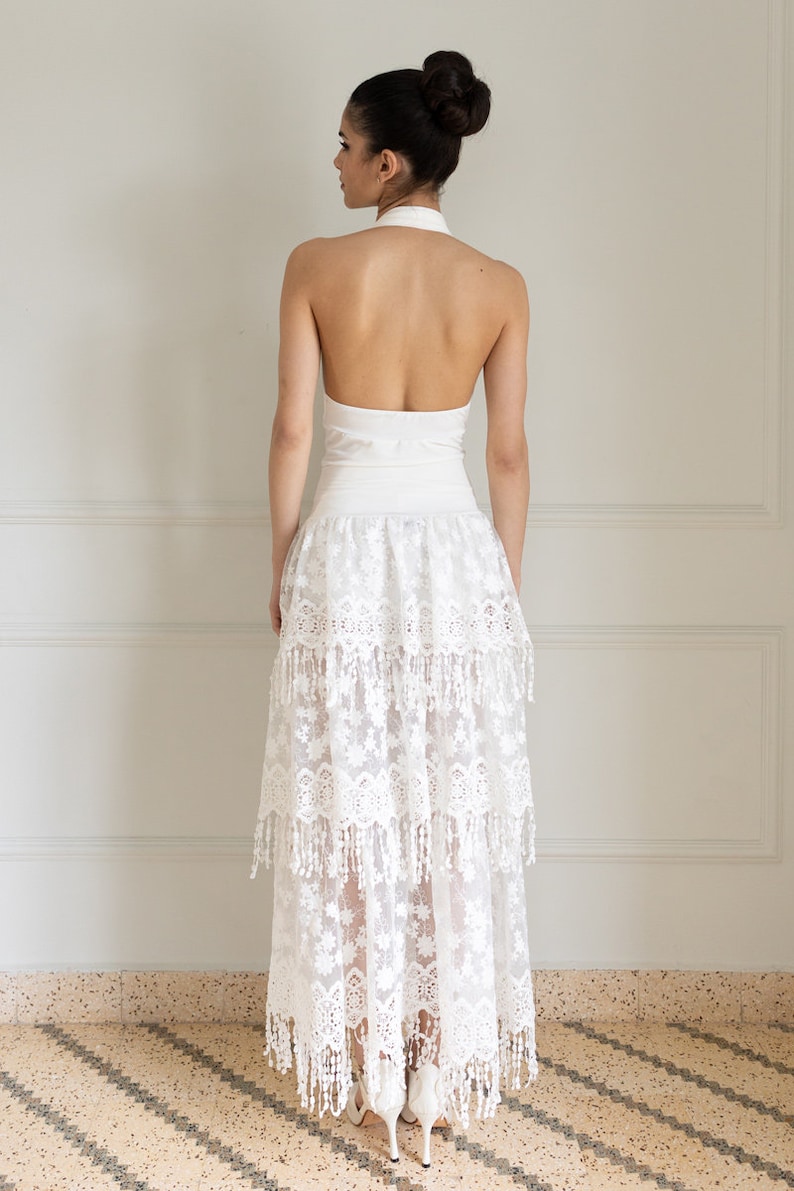 May include: A white halter top with a white lace skirt. The skirt has multiple layers and a fringe trim.