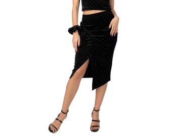May include: Black velvet midi skirt with a front slit and ruched detailing. The skirt is decorated with small, evenly spaced, silver-coloured dots. The model is wearing black strappy heels. The skirt is part of a set.
