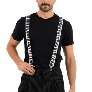 May include: A person wearing a black t-shirt and black and white striped pants with piano key suspenders.