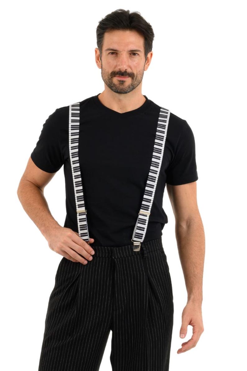 May include: A person wearing a black t-shirt and black and white striped pants with piano key suspenders.