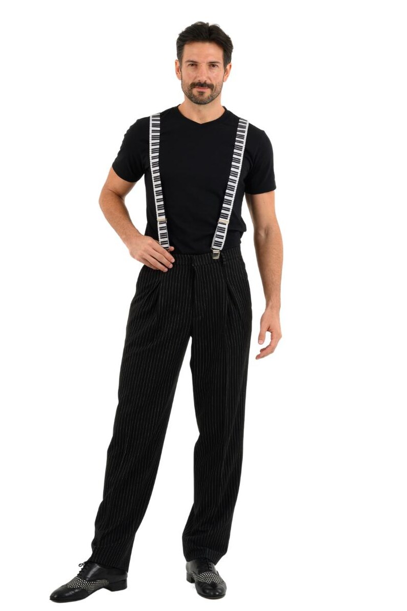 May include: A man wearing a black t-shirt and black pinstripe pants with white piano key suspenders.