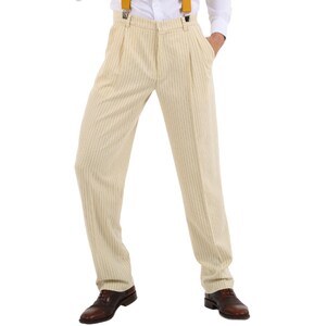 May include: Cream-colored striped pants with a high waist and pleats. The pants are worn with a white shirt and yellow suspenders.