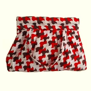 May include: A patterned tote bag with a repeating design in red, white, and brown. The bag has a rectangular shape with a folded top and two handles. The fabric has a wavy, interlocking pattern.