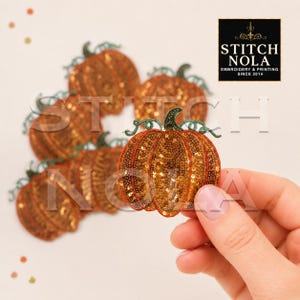 May include: A collection of pumpkin-shaped embroidered patches featuring orange sequins and dark green stems. The patches are arranged in a cluster, with one held up to show detail. A black logo in the corner reads STITCH NOLA EMBROIDERY & PRINTING SINCE 2014.