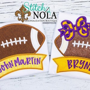 May include: Two white shirts with embroidered footballs and names. The shirt on the left has a brown football with white stitching and the name "John Martin" in purple letters on a yellow banner. The shirt on the right has a brown football with white stitching and a purple bow with yellow polka dots. The name "Brynn" is in purple letters on a yellow banner.