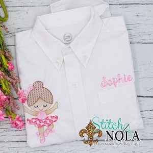 May include: White button-down shirt with pink embroidery of a ballerina girl with brown hair and a pink tutu. The shirt also has the name "Sophie" embroidered in pink on the right side of the chest. The text "Stitch Nola Personalization Boutique" is embroidered on the bottom right corner of the shirt.