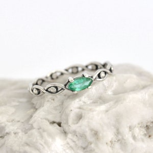 May include: A silver ring with a green gemstone set in a twisted band.