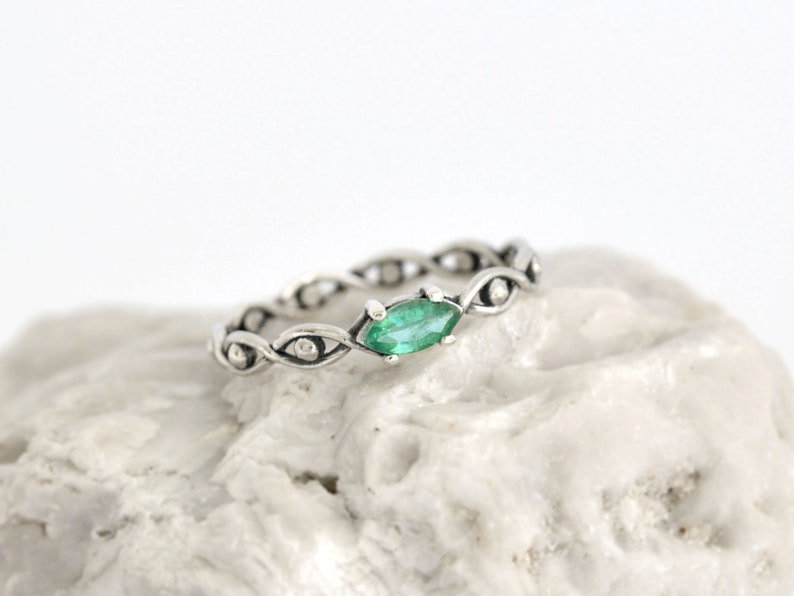 May include: A silver ring with a green gemstone set in a twisted band.