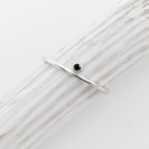 May include: A simple silver band ring with a small black gemstone.