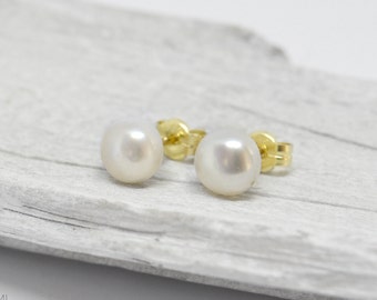 May include: A pair of pearl stud earrings with gold settings. The pearls are white and round.