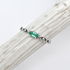 May include: A silver ring with a green gemstone set in a twisted band.
