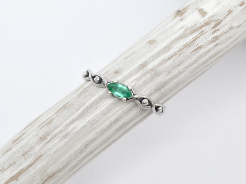 May include: A silver ring with a green gemstone set in a twisted band.