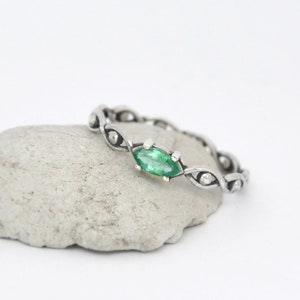 May include: A silver ring with a green marquise-shaped gemstone set in a delicate, twisted band.