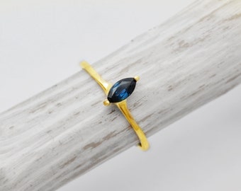 May include: A gold ring with a marquise-shaped blue gemstone.