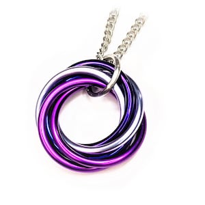May include: A silver chain necklace with a pendant of interlocking rings in purple and silver. The pendant has a circular design, with the rings intertwined. A striking piece of jewellery, suitable for everyday wear or special occasions.