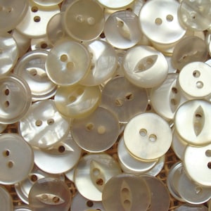 May include: A collection of white pearl buttons with two or four holes. The buttons are various sizes and shapes, including round, oval, and teardrop.