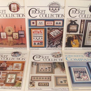 May include: A collection of cross-stitch pattern booklets from "The Cricket Collection." The covers feature framed samplers, teddy bears, and winter scenes. The booklets are designed by Vicki Hastings and Karon Hyslop.