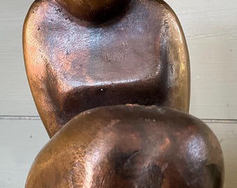 ピンク色の大理石の台座の上に様式化された女性の体を描いたブロンズ