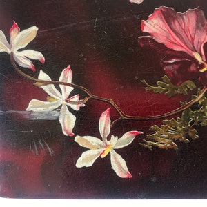 May include: A close-up of a dark red background with a white flower and a pink flower. The flowers are painted on the surface and have a vintage look.