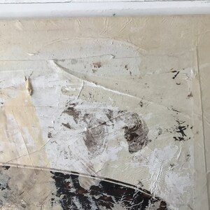 Op de afbeelding: Abstract schilderij op canvas met witte, bruine en zwarte verf. De verf is aangebracht in een dikke, textuurrijke laag, waardoor een gevoel van diepte en beweging ontstaat.