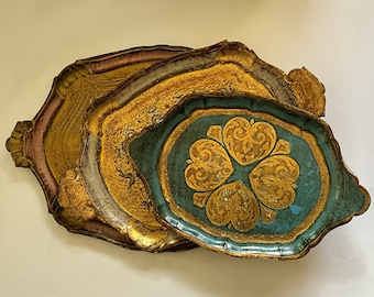 May include: A set of three decorative trays with intricate gold and blue designs. The top tray features a floral pattern in the center, while the bottom two trays have a more abstract design.