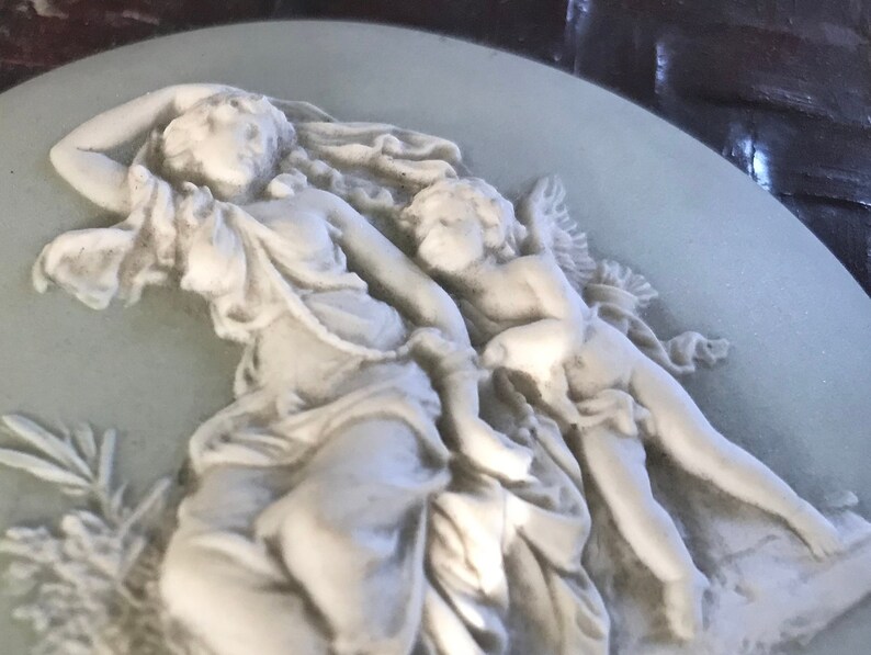 probably Wedgwood Small round green china plate with antique decor of a woman with angel