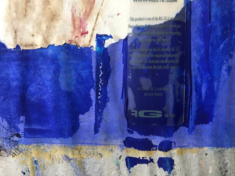 May include: A close-up of a blue and white label with the text "This product is one of the RG 512 Collection. Our collection has been designed to answer your customer's demand with special care regarding design, material and comfort."  The label also includes the text "AUTHENTIC GARMENT REGISTERED" and the logo "RG 512".
