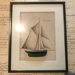 May include: A framed black and white drawing of a sailboat with the text "Cobre "Tilda" written in the top right corner of the image.