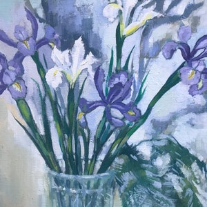 Peut inclure: Un bouquet d'iris violets et blancs dans un vase en verre transparent. Les fleurs sont disposées de manière lâche et naturelle, et le vase est posé sur un fond gris clair.