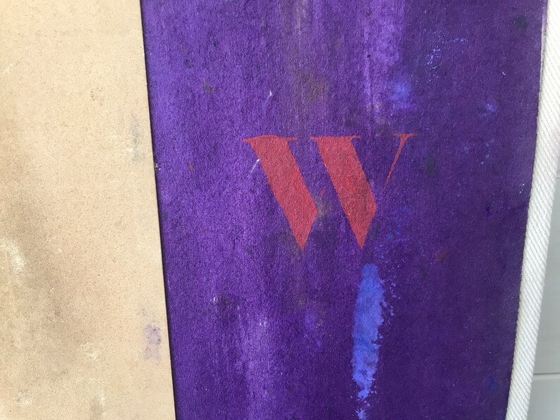 May include: A close-up of a purple surface with a large red "W" painted on it. The surface is textured and has a few spots of blue paint.