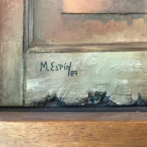 Op de afbeelding: Een close-up van de handtekening van een schilderij, "M. Espin 187", geschreven in zwarte inkt op een lichtgrijze achtergrond.