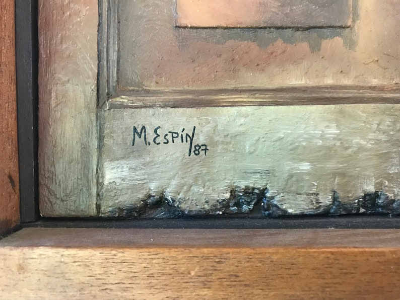 Op de afbeelding: Een close-up van de handtekening van een schilderij, "M. Espin 187", geschreven in zwarte inkt op een lichtgrijze achtergrond.