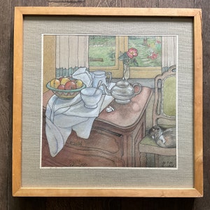 May include: A still life painting of a table setting with a teapot, bowl of fruit, and a cat sleeping on a chair. The painting is framed in a wooden frame.