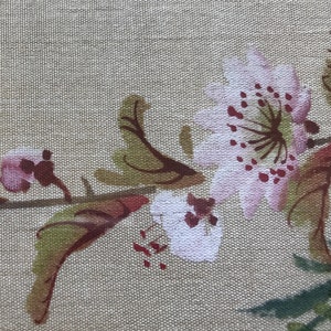 May include: A beige fabric with a floral design featuring pink and white flowers with brown stems and leaves.