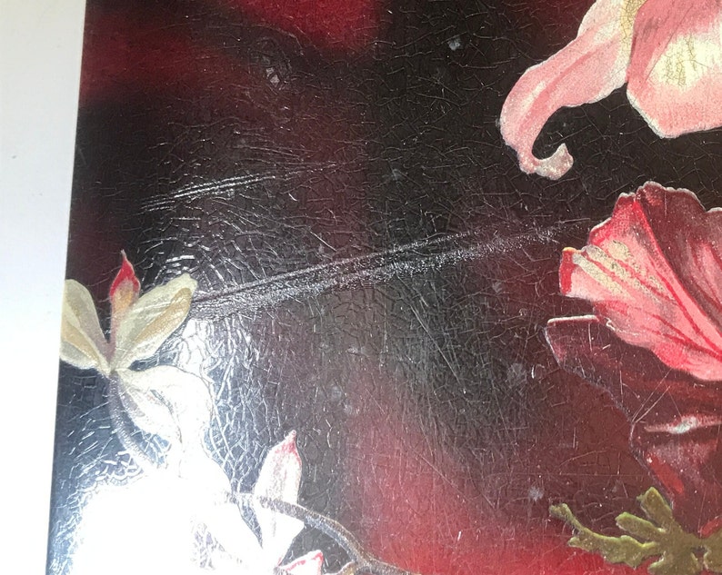 May include: Close-up of a vintage postcard with a floral design. The postcard features pink and white flowers on a dark background with a textured surface.
