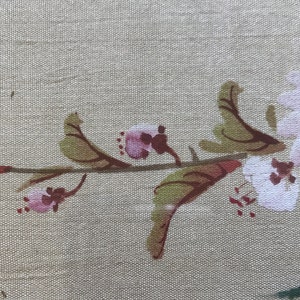 May include: A delicate branch of pink and white flowers with green leaves painted on a beige fabric background.
