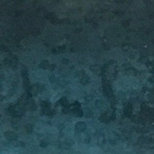 May include: A dark teal blue textured background with a faint, blurry inscription.