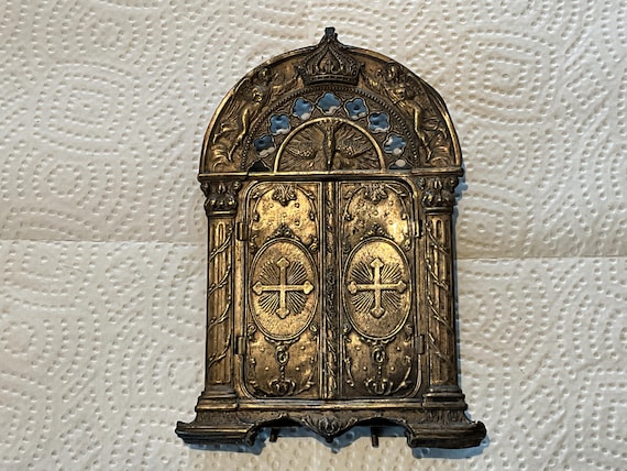 Encadrement en métal qui peut s’ouvrir pour permettre de voir l’image placée à l’intérieur. Décor religieux, anges et croix